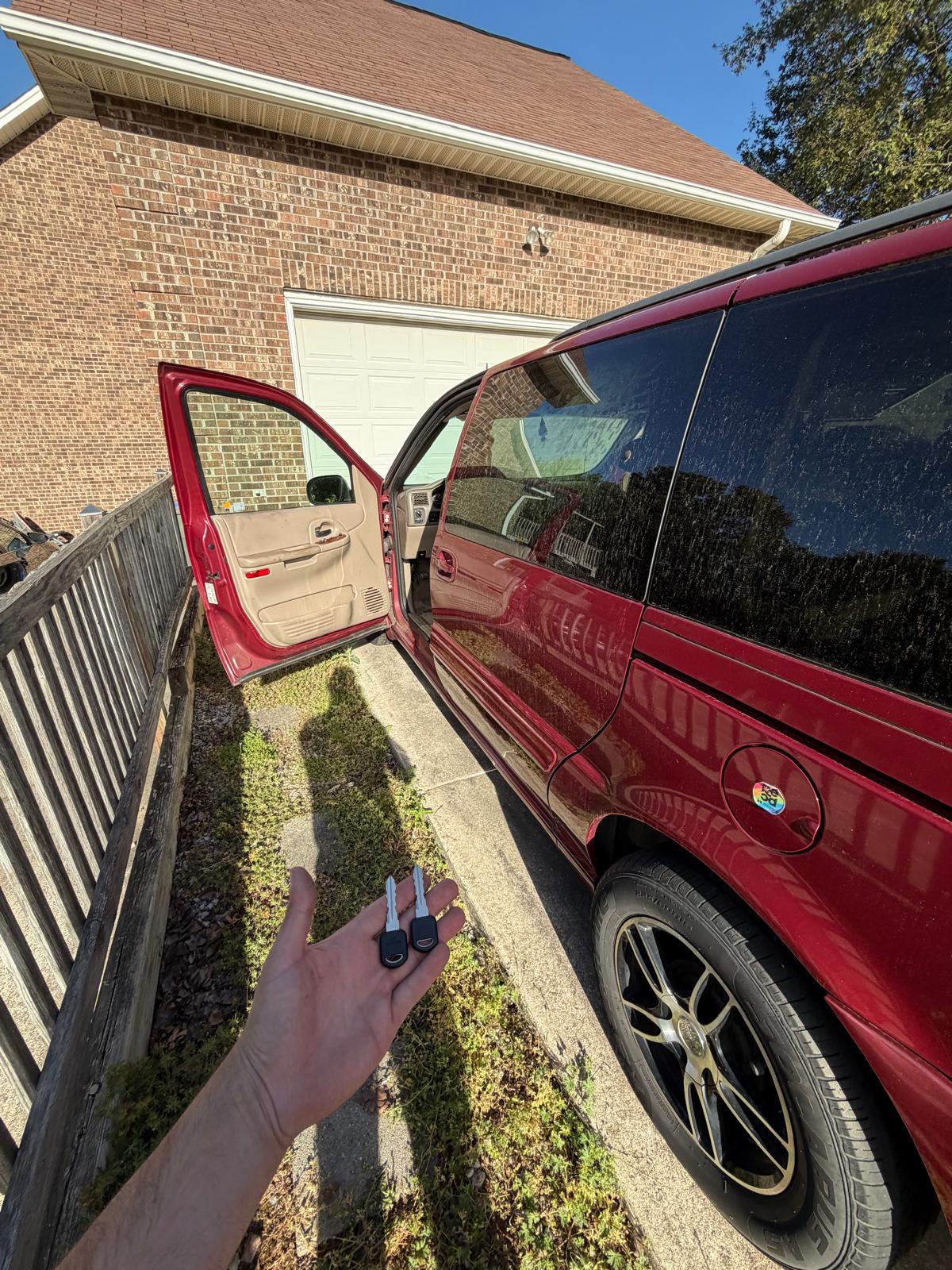 Mobile locksmith holding newly generated Chevrolet transponder keys next to a red Chevy truck during a custom Locksmith Services job in Davidson