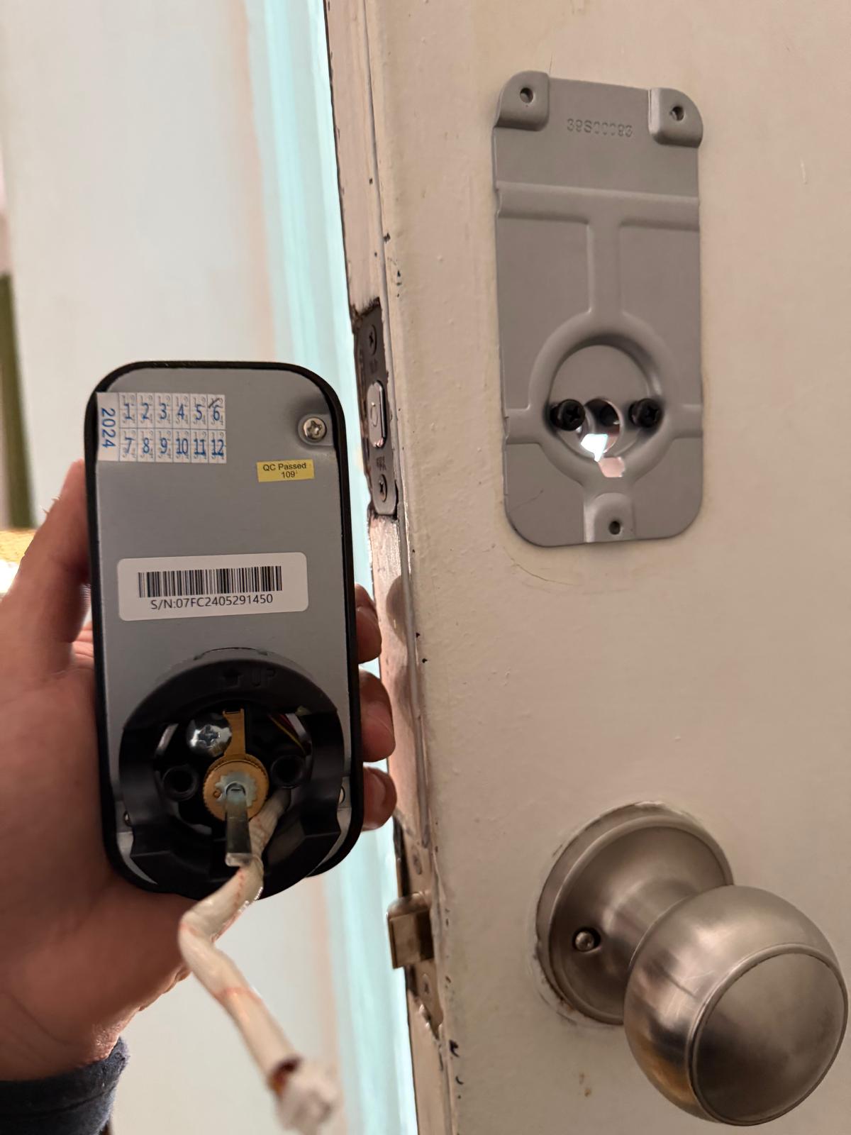 Locksmith installing an electronic smart keypad lock on a wooden residential front door in Charlotte, NC NC