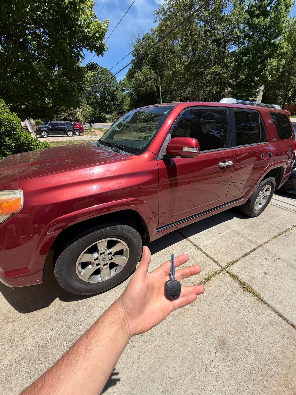 Professional locksmith holding a newly cut transponder key next to a red Toyota SUV in Charlotte in Charlotte, NC NC