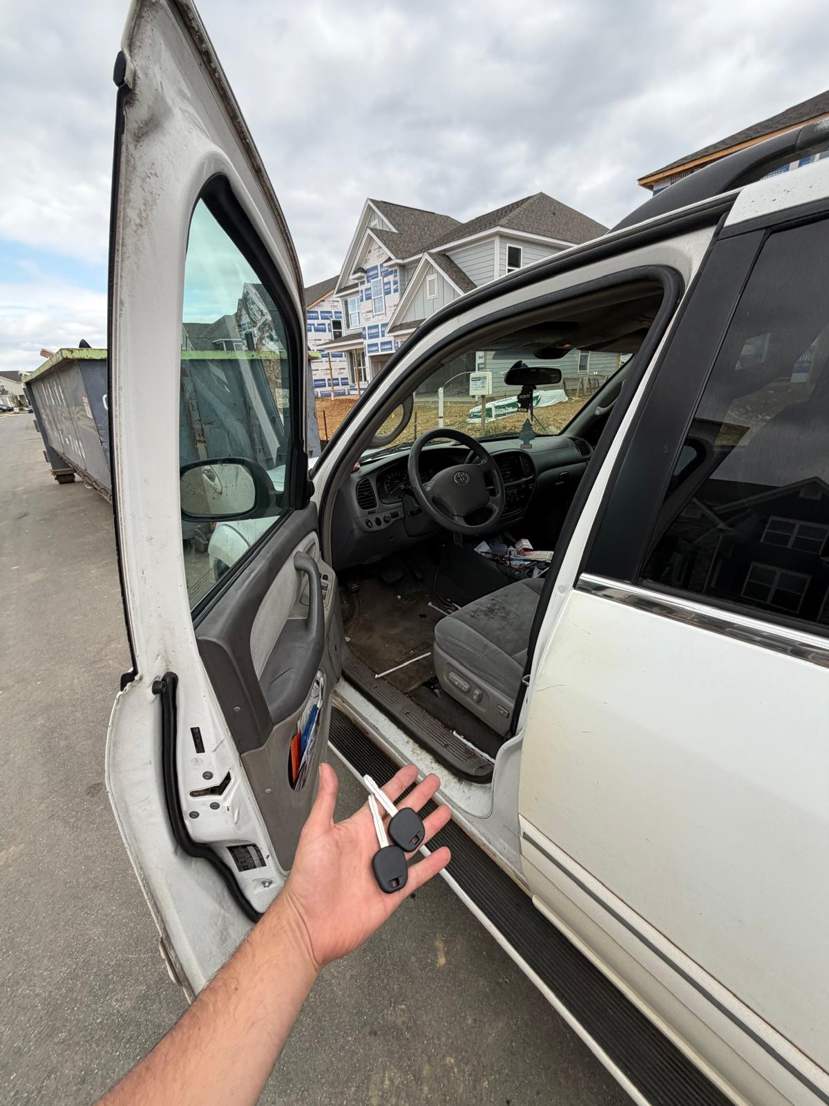 Technician holding new transponder keys next to a white Toyota Land Cruiser SUV during a custom Locksmith Services job in Charlotte, NC