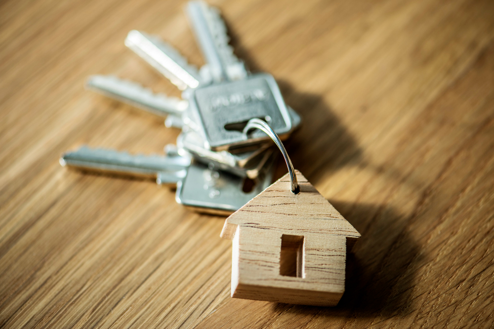 Wooden house keychain attached to house keys, symbolizing reliable locksmith services in Charlotte for lock repair and key cutting.